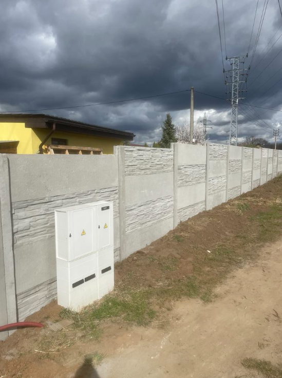 Hotový betonový plot táhnoucí se podél pozemku v Brně