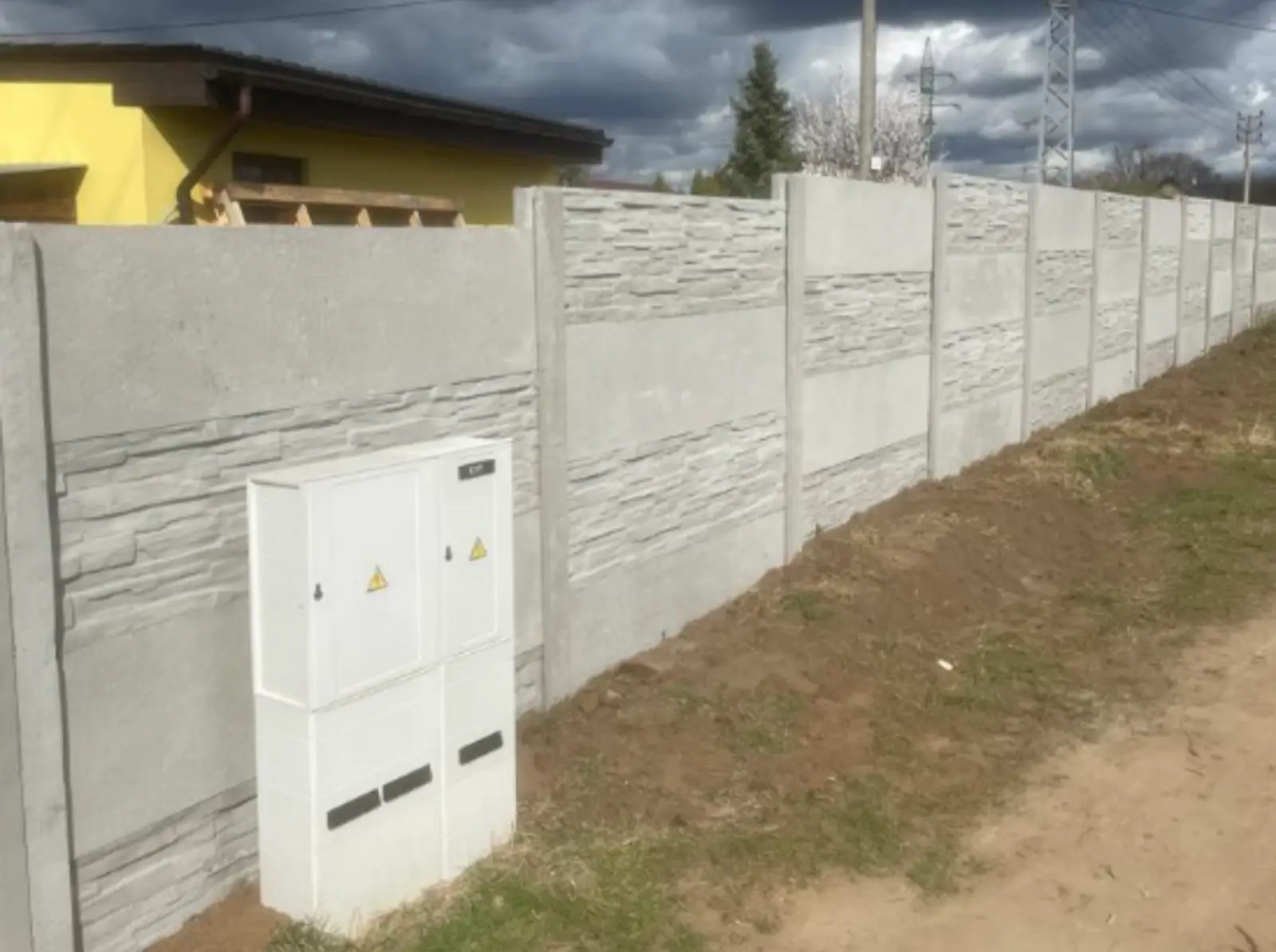 Instalace šedého betonového plotu se vzorem štípaného kamene a hladkého betonu v Kloboukách u Brna.